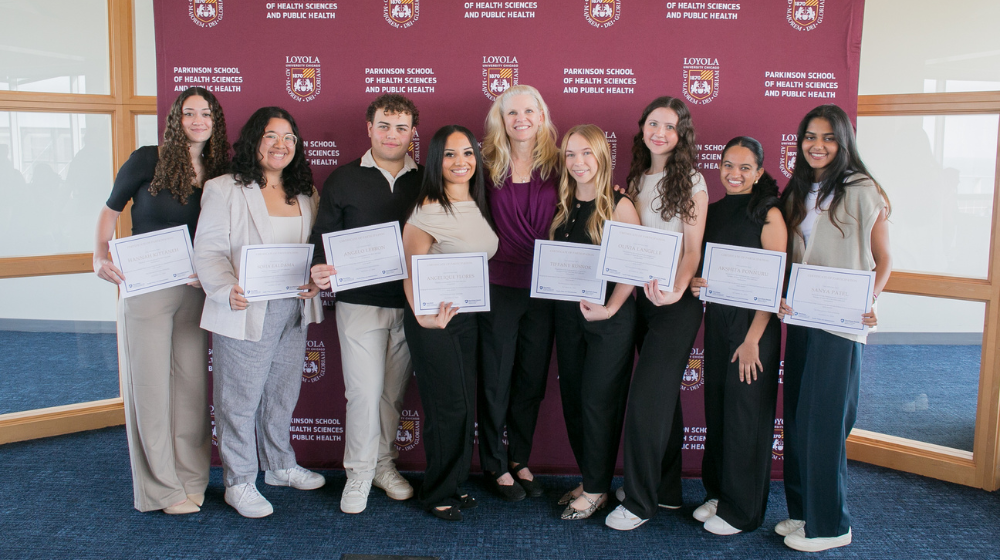 Students holding certificates in front of backdrop